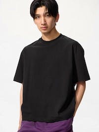 Male model wearing a black boxy cropped cotton T-shirt, shown from the front.