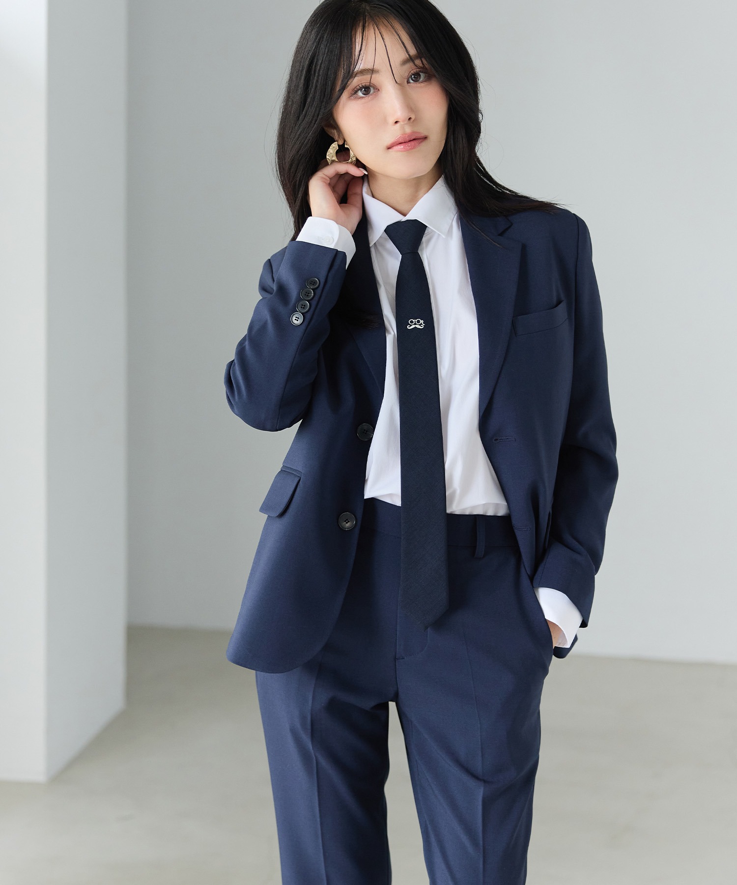 Female model wearing the navy BOYSHE Basic Suit with blazer and matching trousers, a white shirt, and a navy tie.