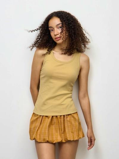 Front view of a model wearing the ribbed tank top (polyester) in a light mustard color.