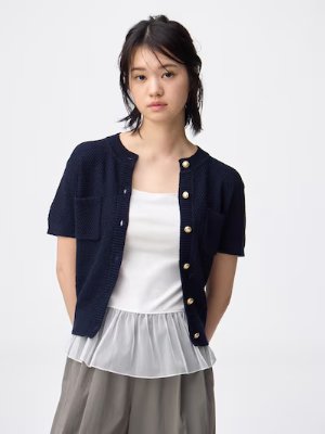Model wearing the white peplum camisole layered under a navy cardigan.