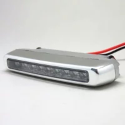 Slim silver LED daytime running light with nine LEDs and red and black wires on a white background.