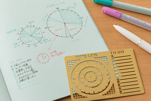 Diary template ruler with TIME LOG and TO DO stencil placed on a dotted notebook page next to pens and drawn time-log diagrams.