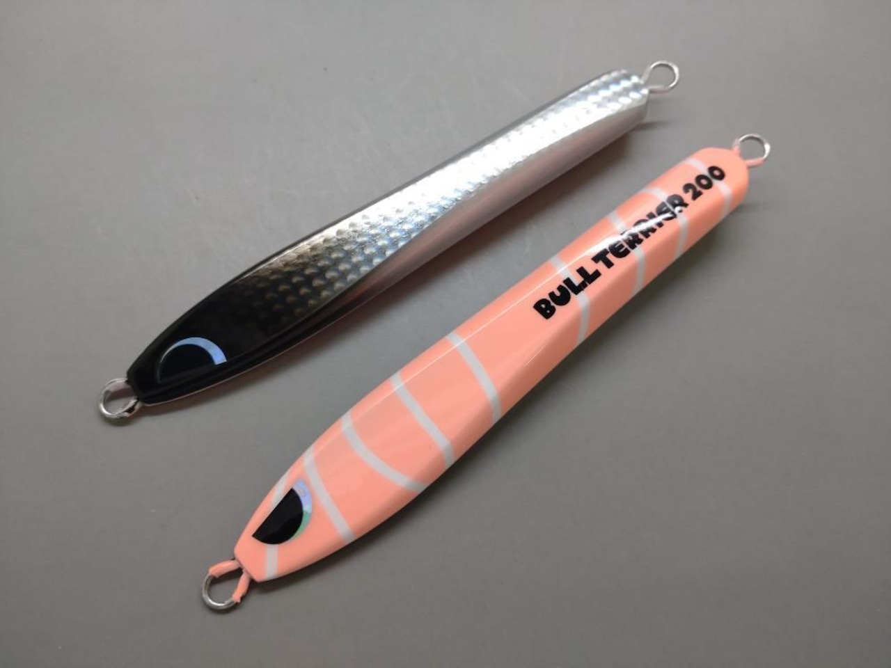 Two BREED Bull Terrier 200g fishing lures in silver/black and pink striped original colors shown side by side.