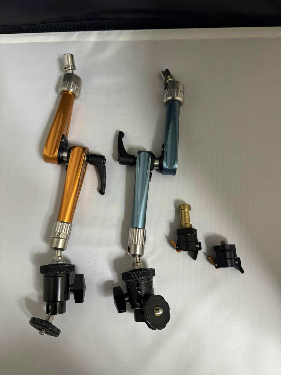 Two support arms (one orange, one teal) with quick-release attachments and clamp accessories laid flat on a light background.
