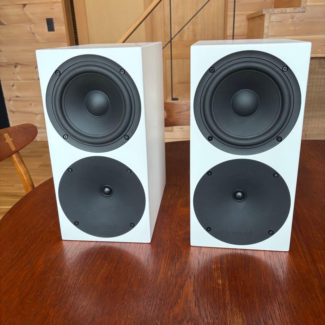 Pair of white Buchardt S400mk2 speakers shown front-facing on a wooden table.