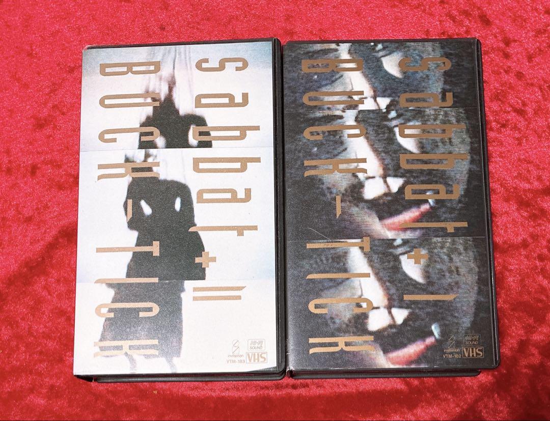 Two BUCK-TICK VHS videotapes for "sabbat + I Ⅱ" laid side by side on a red fabric background showing their front covers.