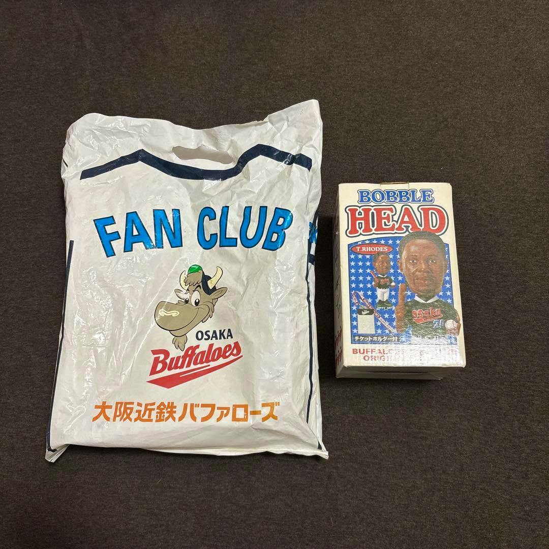 Boxed T. Rhodes (タフィ・ローズ) Buffaloes fan club bobblehead displayed next to an Osaka Buffaloes fan club plastic bag.