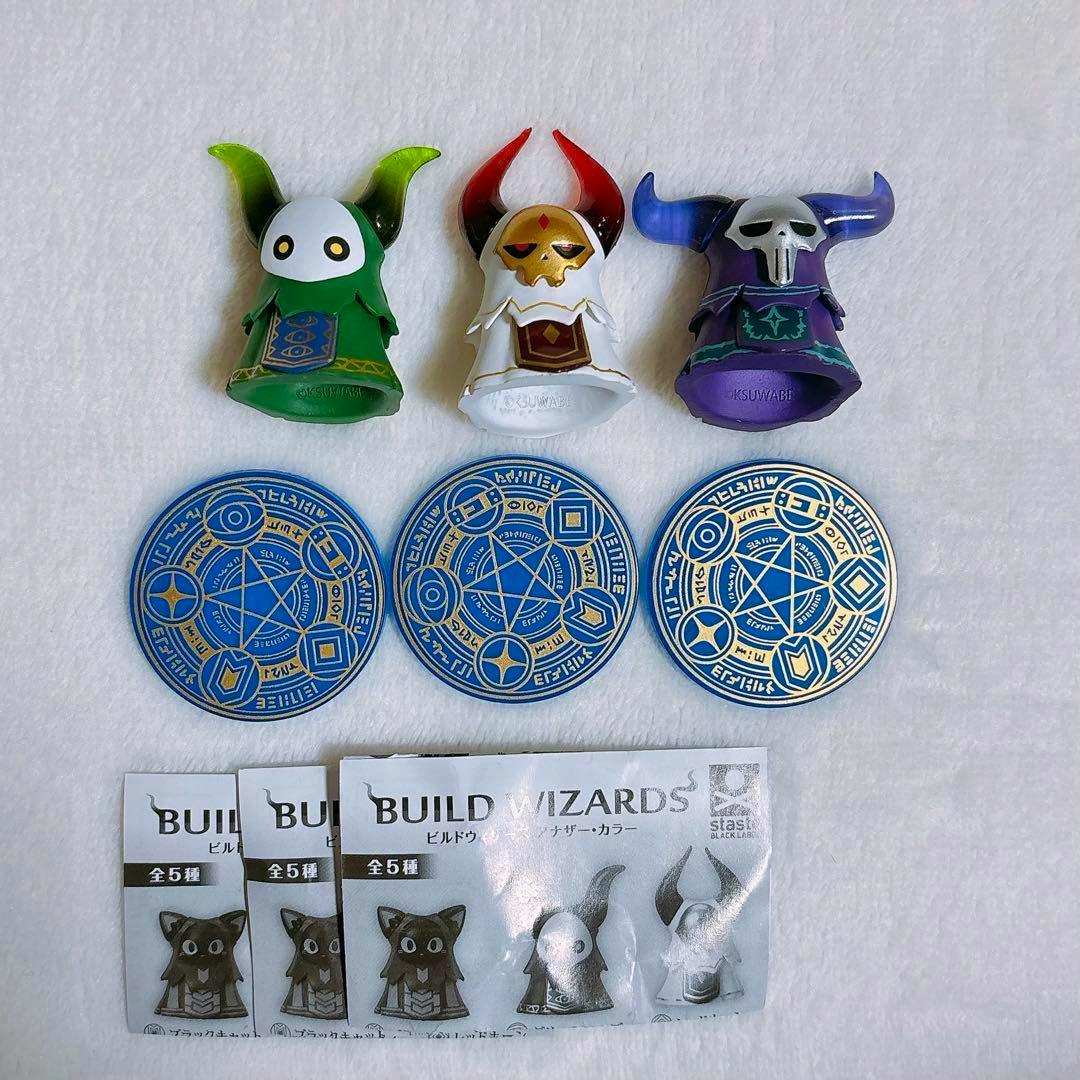 Front view of three Build Wizards plastic figure variants with three blue circular magic discs and the product paper on a white background.