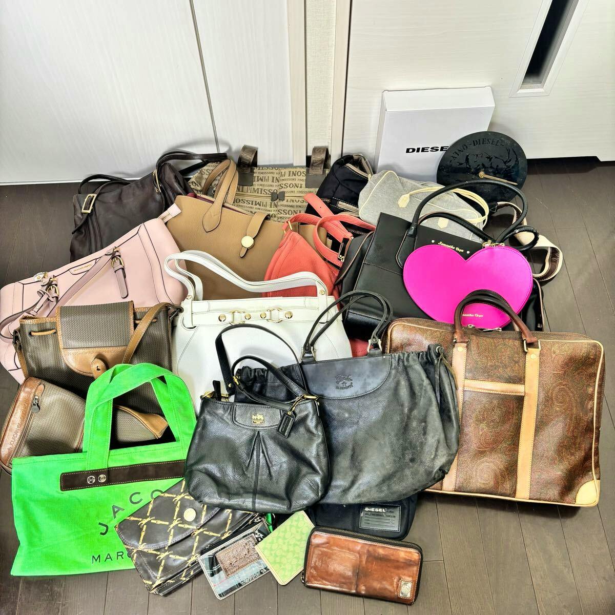 Many handbags and small wallets arranged on a floor displaying a bulk set of bags.