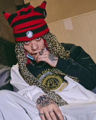 Person wearing a red and black striped knit beanie with pointed "bunny" ears and a round front patch.