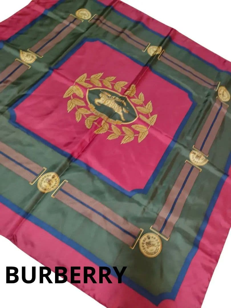 Silk scarf laid flat showing a central horse emblem and laurel wreath on red and green background.