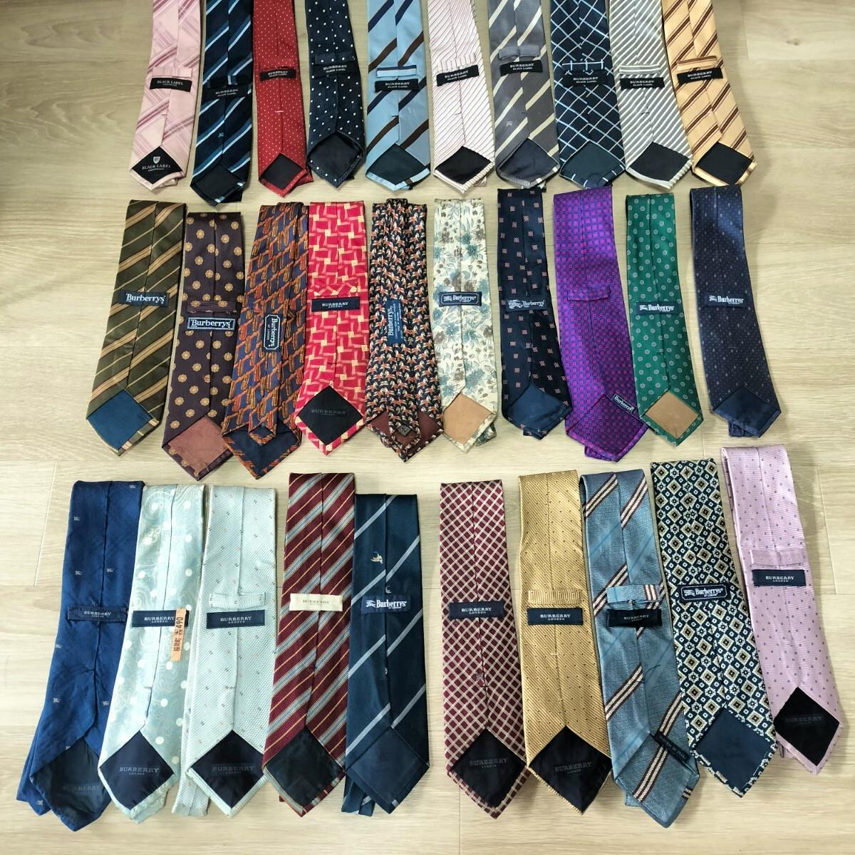 Multiple BURBERRY neckties arranged on a floor showing various patterns and visible brand labels.