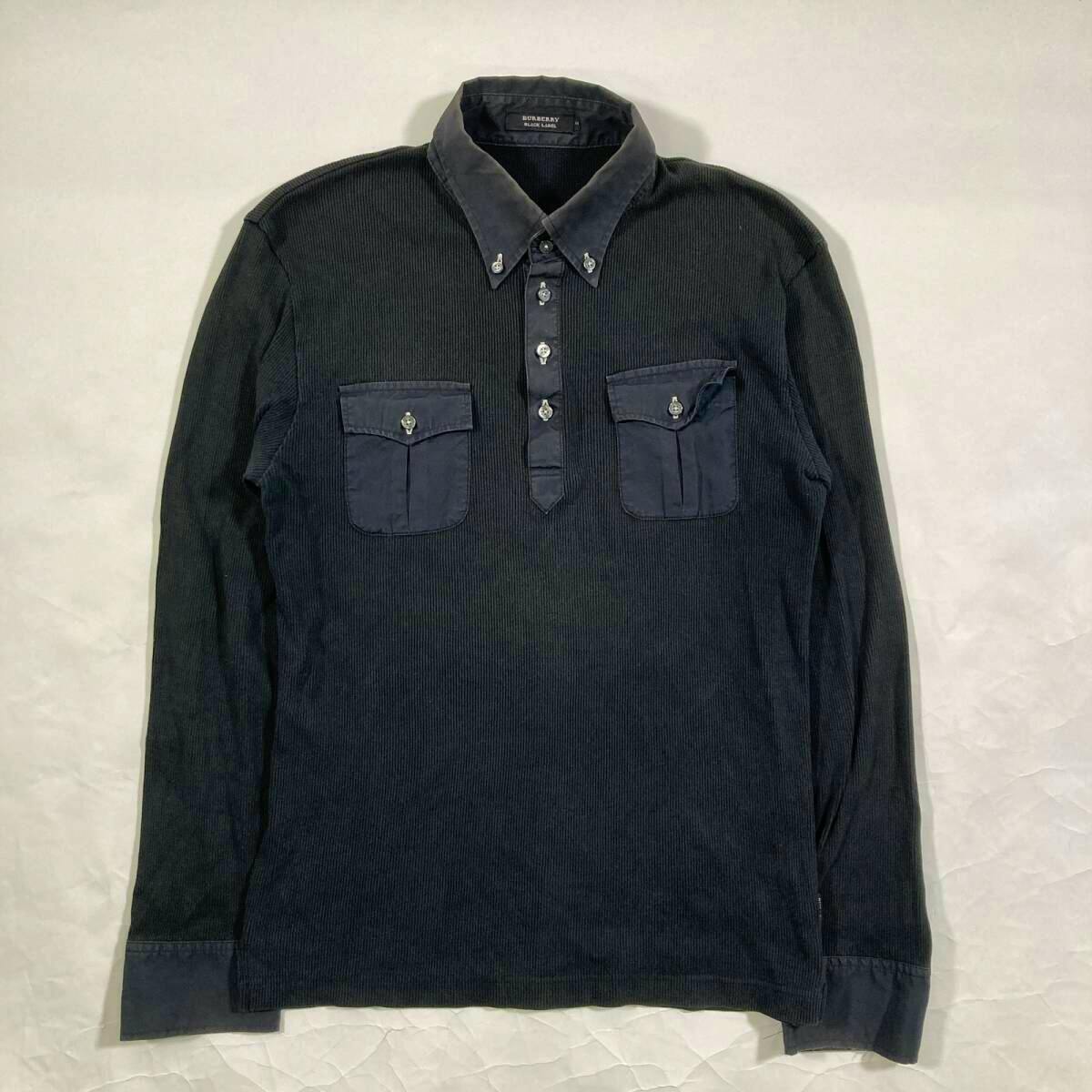 Flat-lay front view of a Burberry Black Label men's long-sleeve black ribbed cotton shirt with button-down collar, central button placket, and two chest flap pockets.