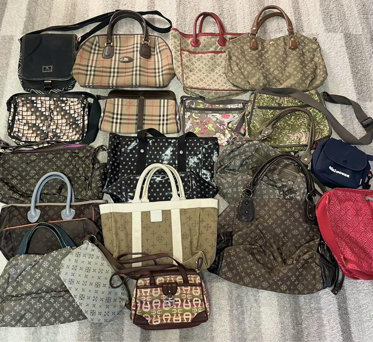 Photo of a large assortment of canvas and leather bags laid out on a floor, showing many different styles and patterns.
