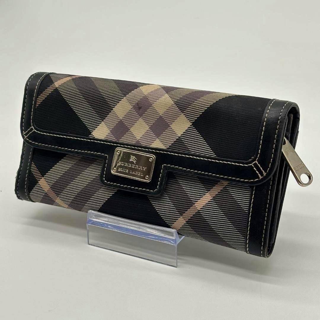 Burberry Blue Label long wallet in Nova check polyester shown angled on a clear stand with its metal logo plate visible.