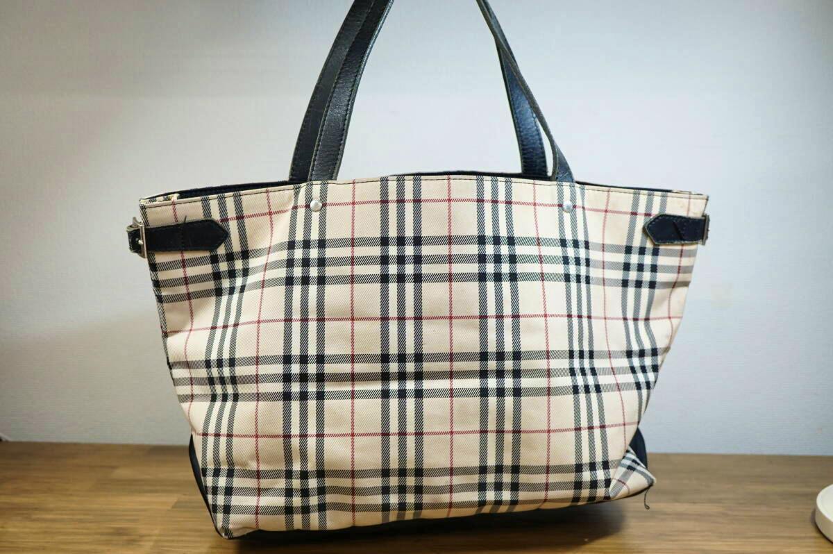 Beige Burberry Blue Label Nova check tote bag with black handles shown on a wooden surface.