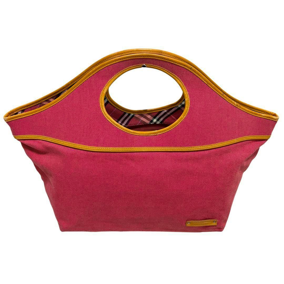 Front view of a pink Burberry Blue Label canvas handbag with round cutout handles, tan trim, and visible Nova check interior.
