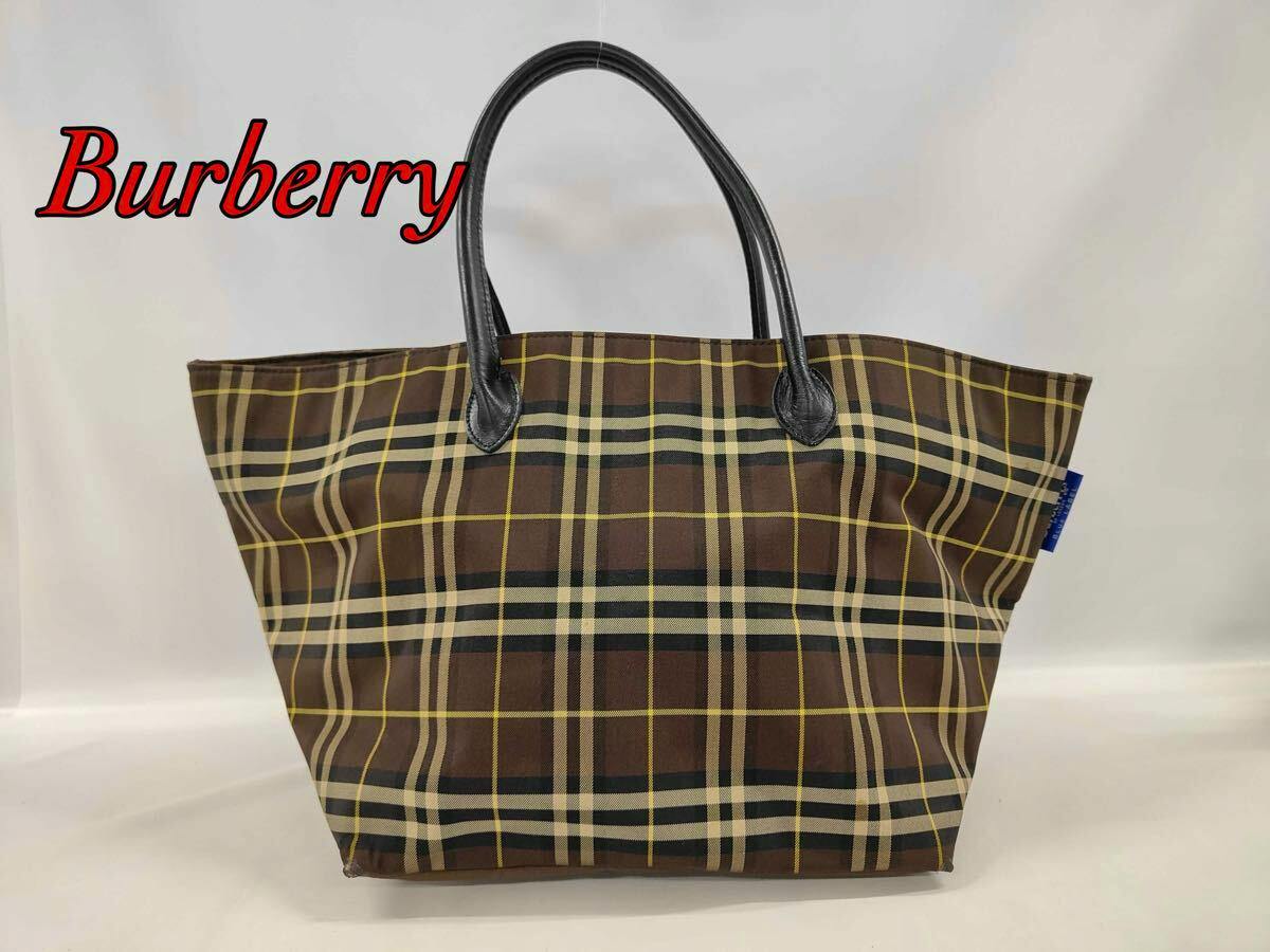Brown Burberry Blue Label Nova Check tote bag with black leather handles on a plain background.