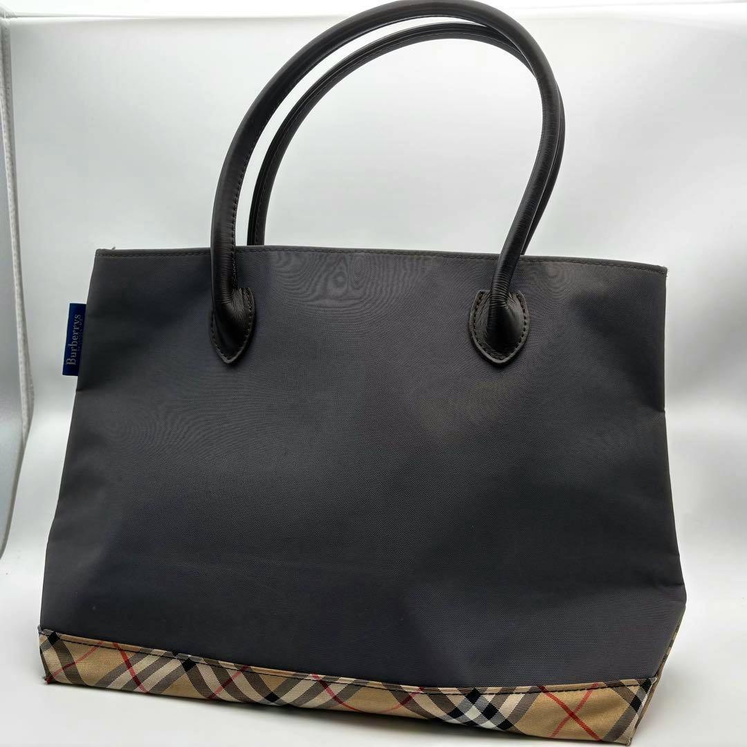 Black Burberry Blue Label nylon tote bag with Nova check trim along the bottom shown against a white background.