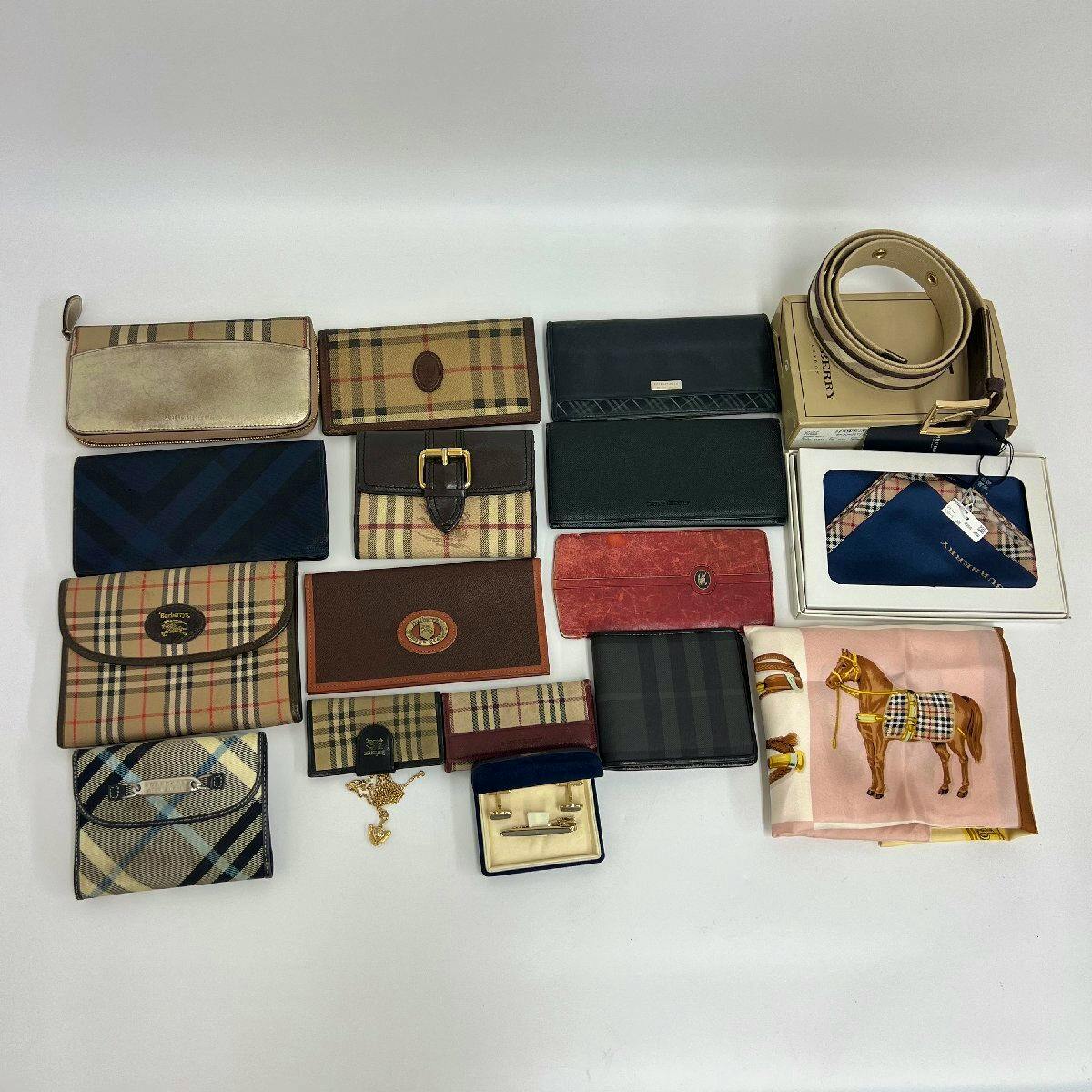 Eighteen Burberry wallets and small accessories arranged flat on a white background, including multiple wallets, a belt, a scarf, and a tie pin.