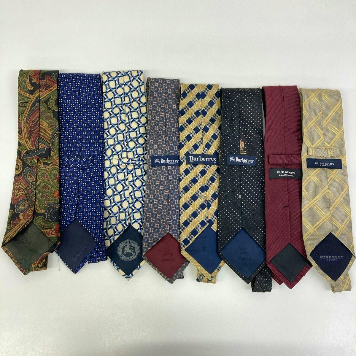 Eight Burberry men's silk neckties in various patterns laid side-by-side on a white background.