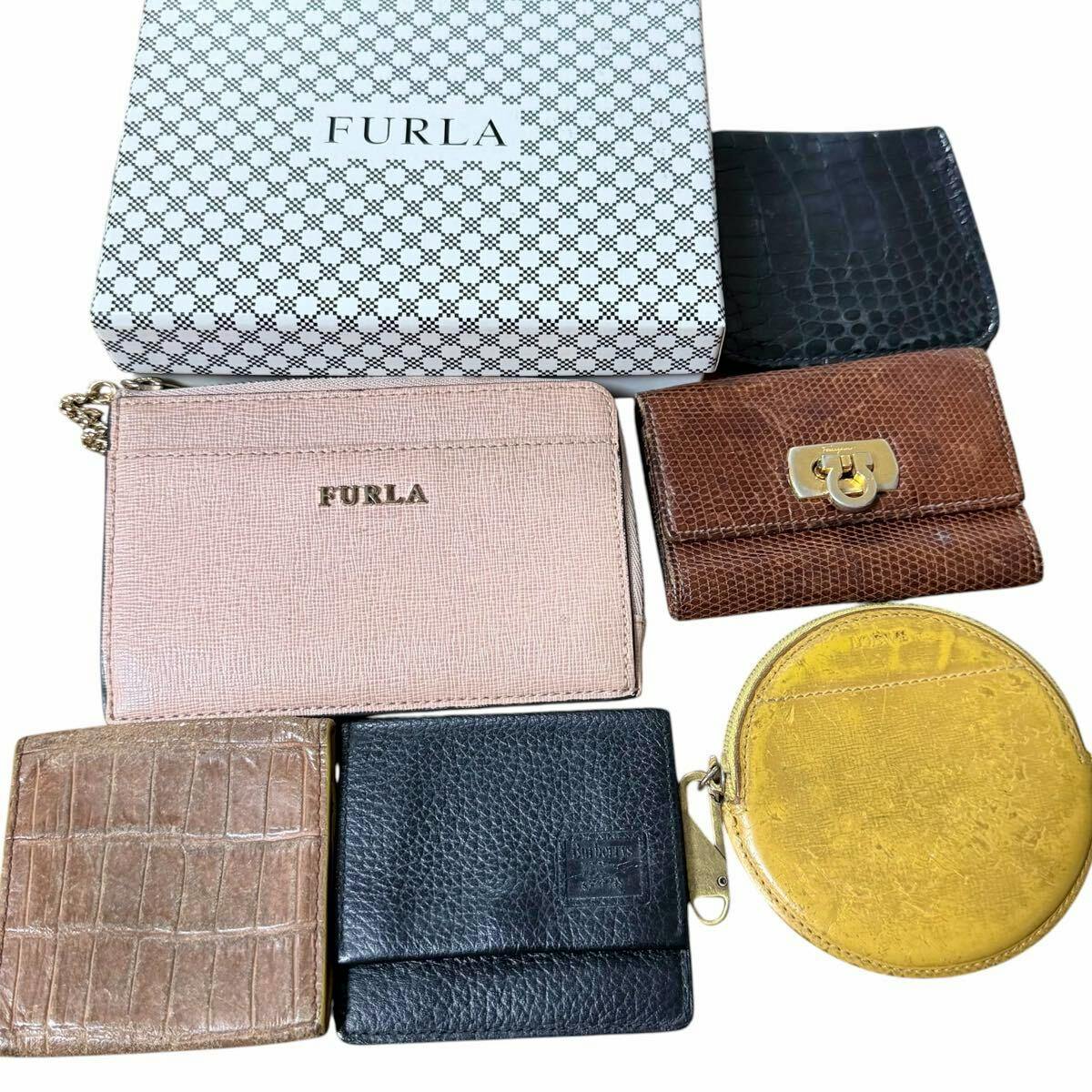 Top-down photo of six wallets and small leather accessories arranged together including a FURLA box.