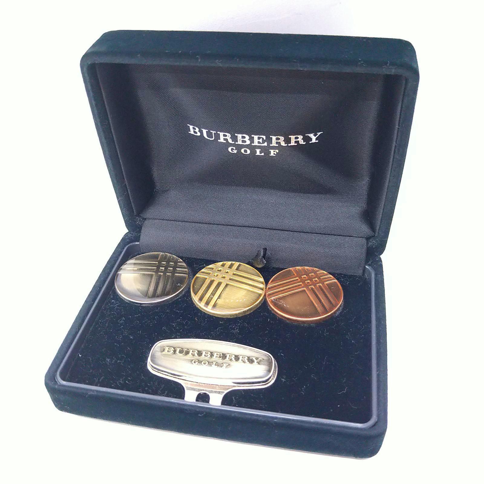 Black Burberry Golf presentation box showing three round gold, silver, and copper golf markers and a Burberry Golf clip.