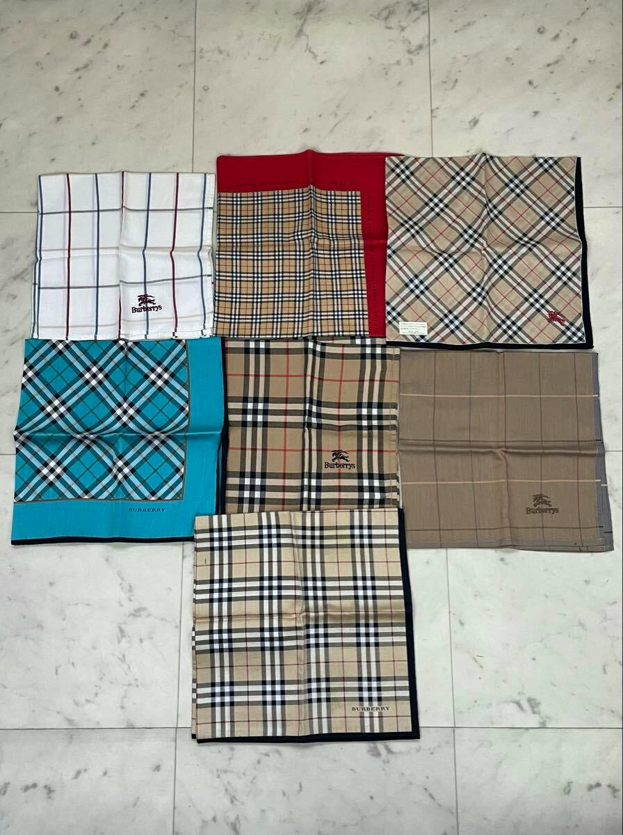Seven Burberry handkerchiefs in various check patterns laid out flat on a tiled floor.