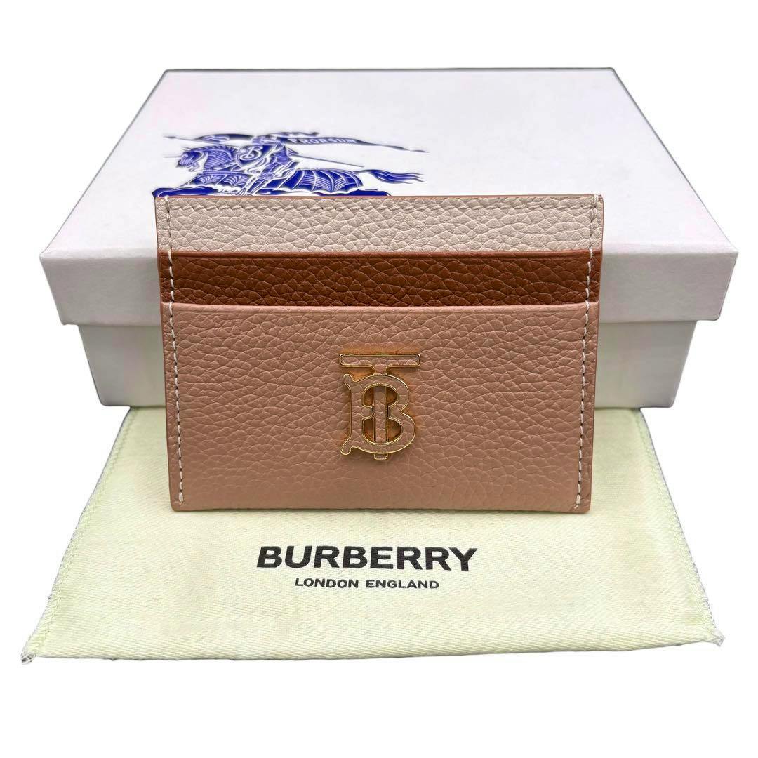 Beige bicolour Burberry cow leather card case with gold TB logo displayed in front of its box and dust bag.