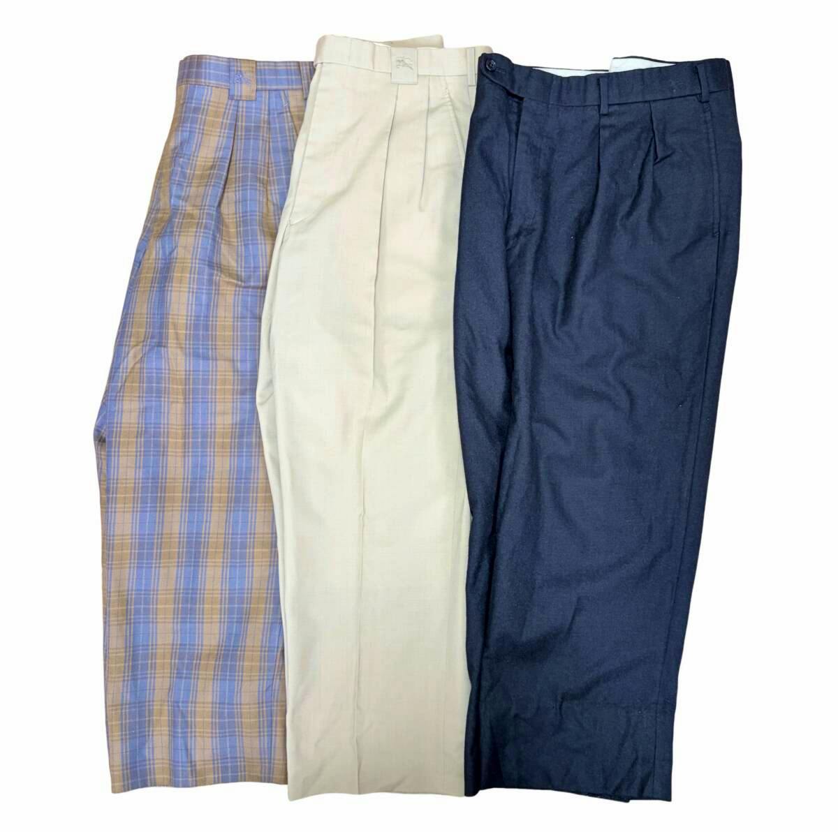 Three pairs of wool pants (plaid, beige, navy) laid flat on a white background.