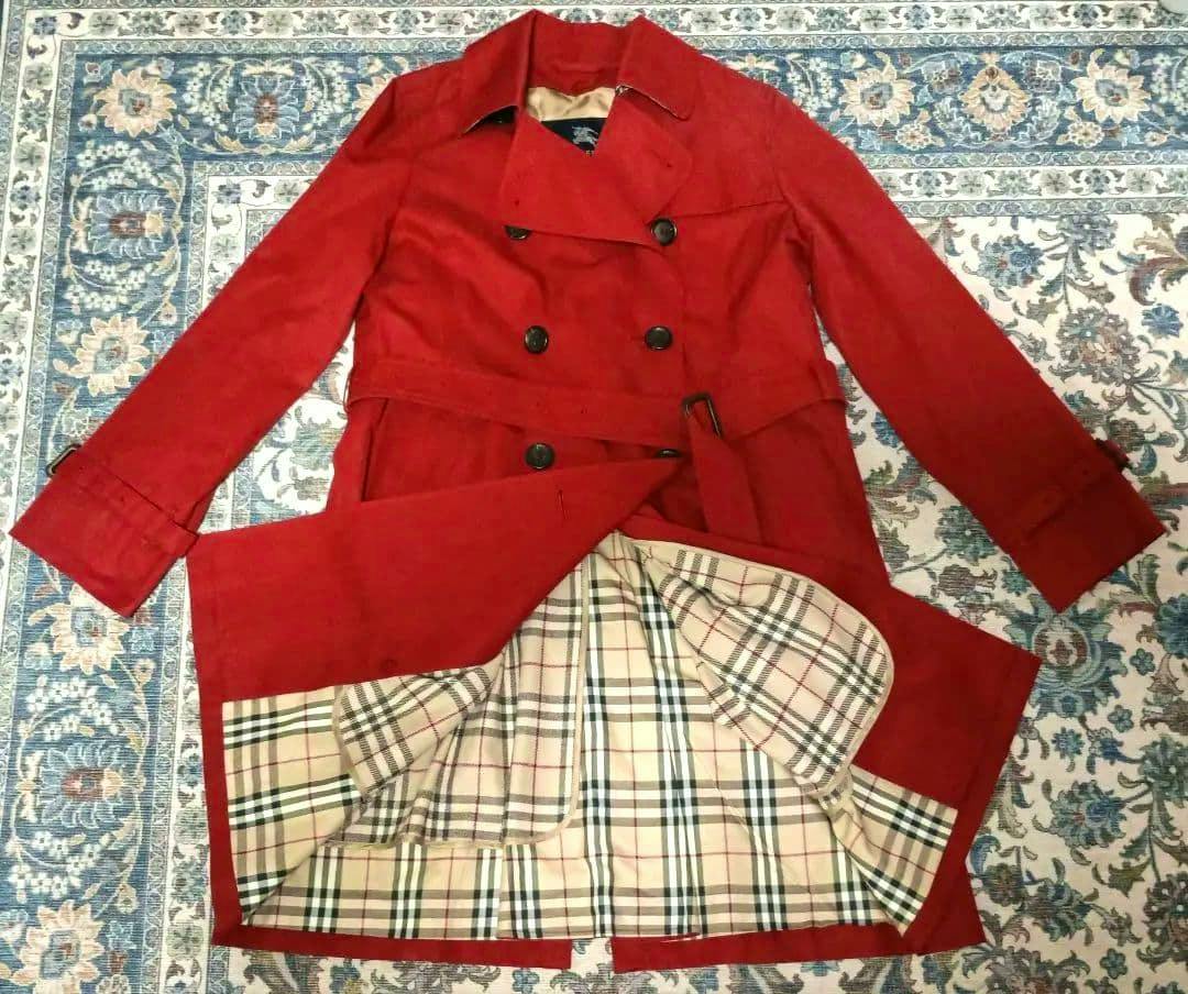 Red Burberry trench coat laid flat with the checked Nova lining exposed.