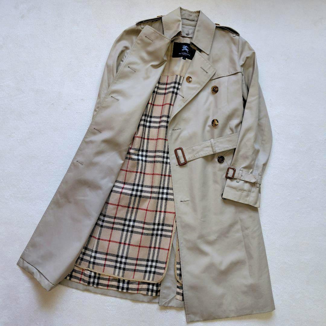Beige Burberry trench coat laid flat with its Nova check liner exposed.