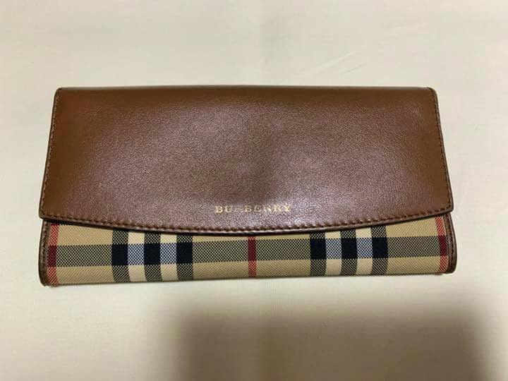 Long Burberry canvas wallet with a brown leather flap and classic check pattern lying on a light surface.