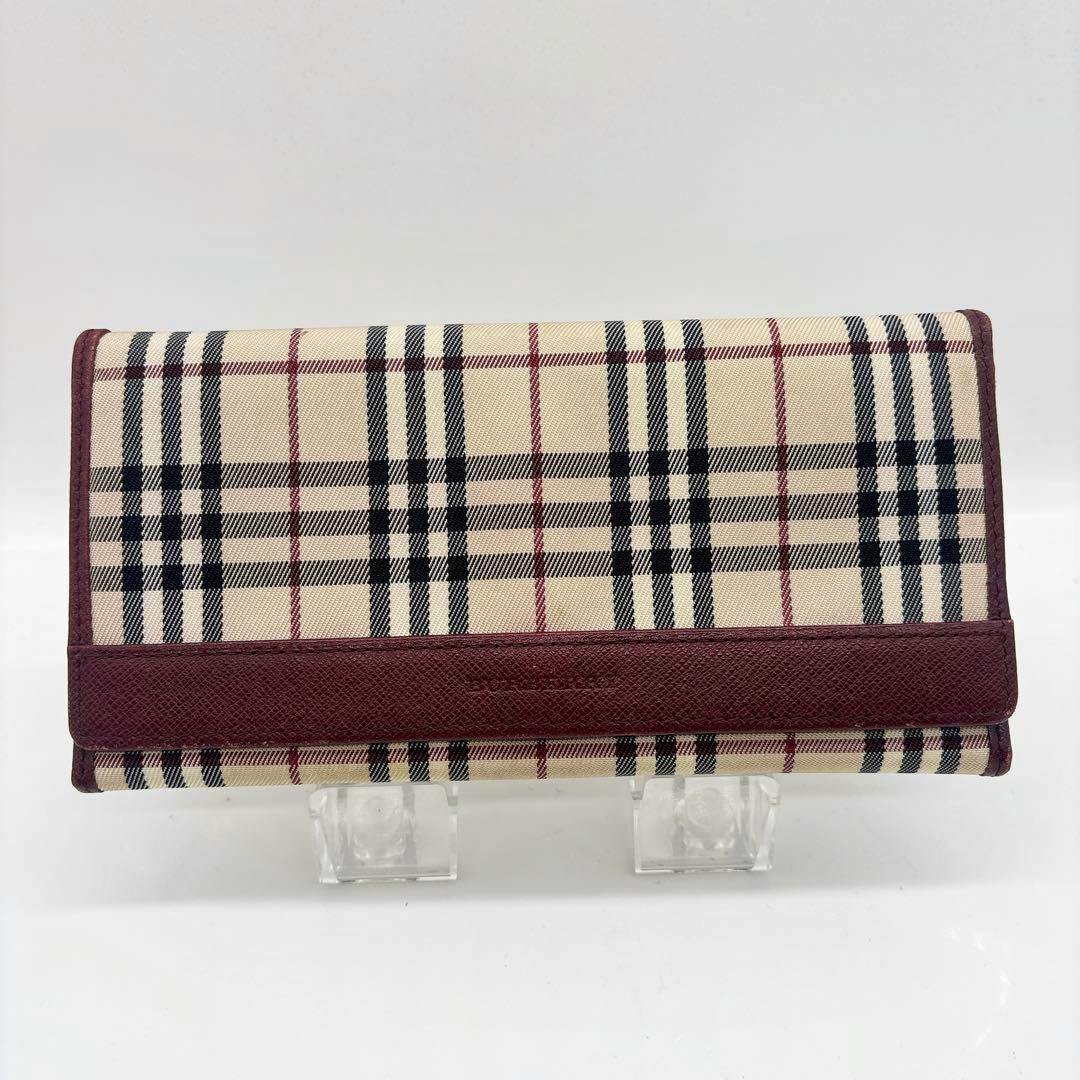 Front view of a Burberry Nova Check canvas and leather bifold long wallet displayed on clear stands.