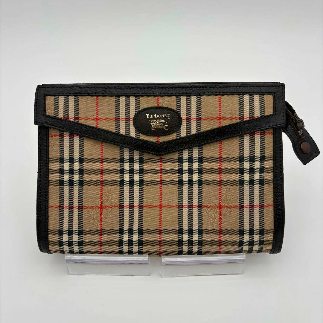 Front view of a Burberry Nova Check brown canvas clutch bag with black trim and horse logo.