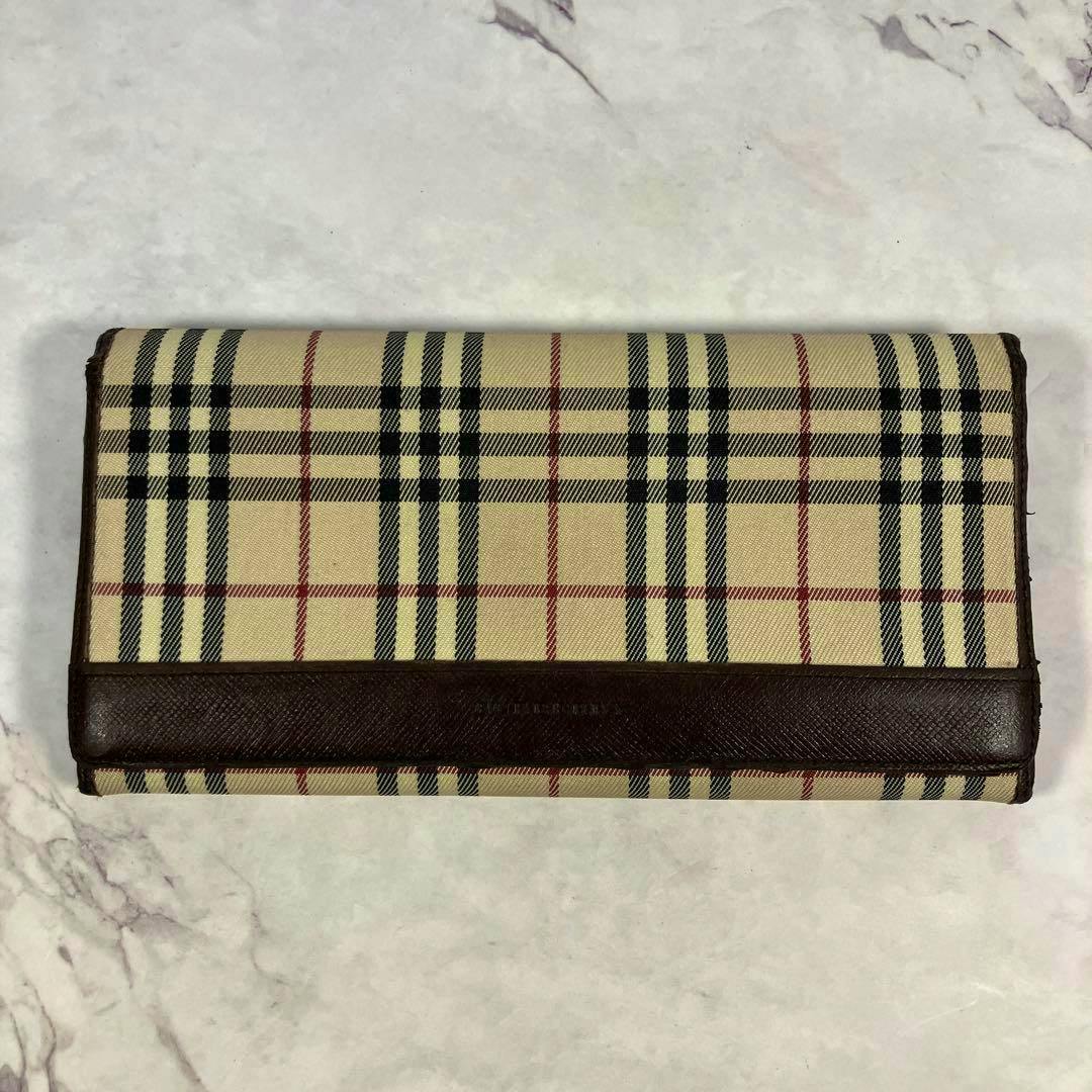 Front view of a Burberry long wallet in Nova Check canvas with brown leather trim on a light background.