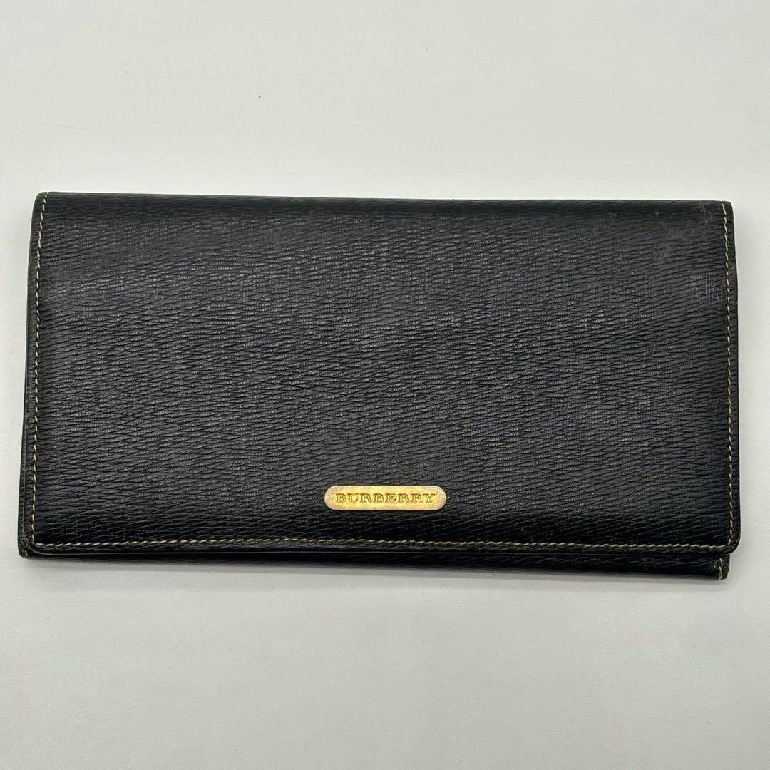 Black Burberry long leather wallet with a small gold BURBERRY metal plaque on the front, shown on a white background.