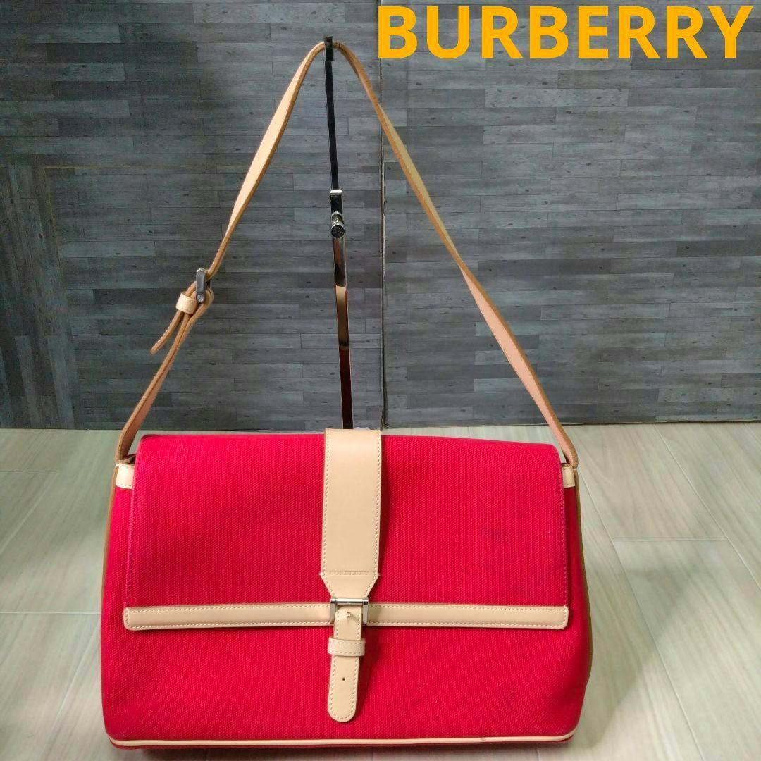 Front view of the red Burberry one-shoulder canvas handbag with beige leather strap and buckle.