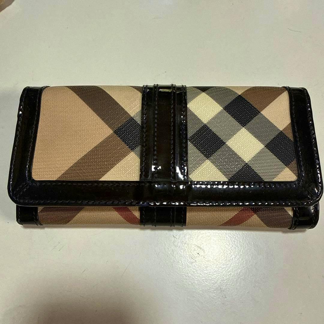 Burberry long wallet in Nova Check canvas with black patent trim shown closed on a white surface.