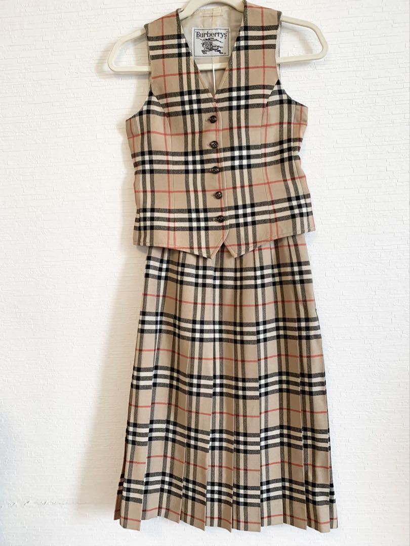 Burberry Nova Check vest and matching pleated skirt displayed on a hanger against a white wall.