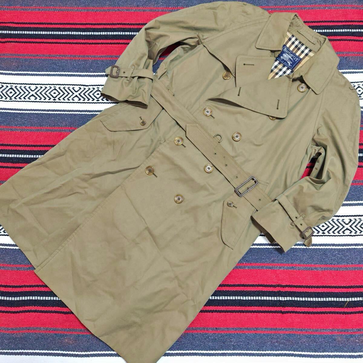 Khaki Burberry trench coat laid flat showing the double-breasted front, belt, and checked lining at the collar.