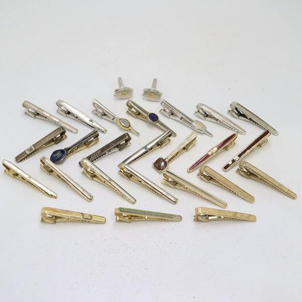 Multiple Burberry tie clips and a pair of cufflinks arranged on a white background.