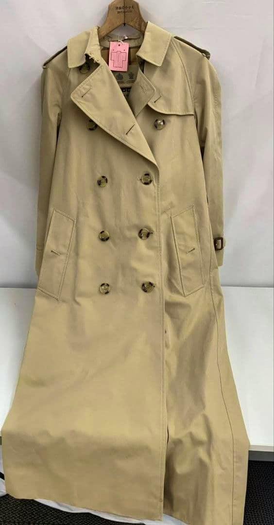Front view of a long beige Burberry women's trench coat hanging on a hanger against a plain background.