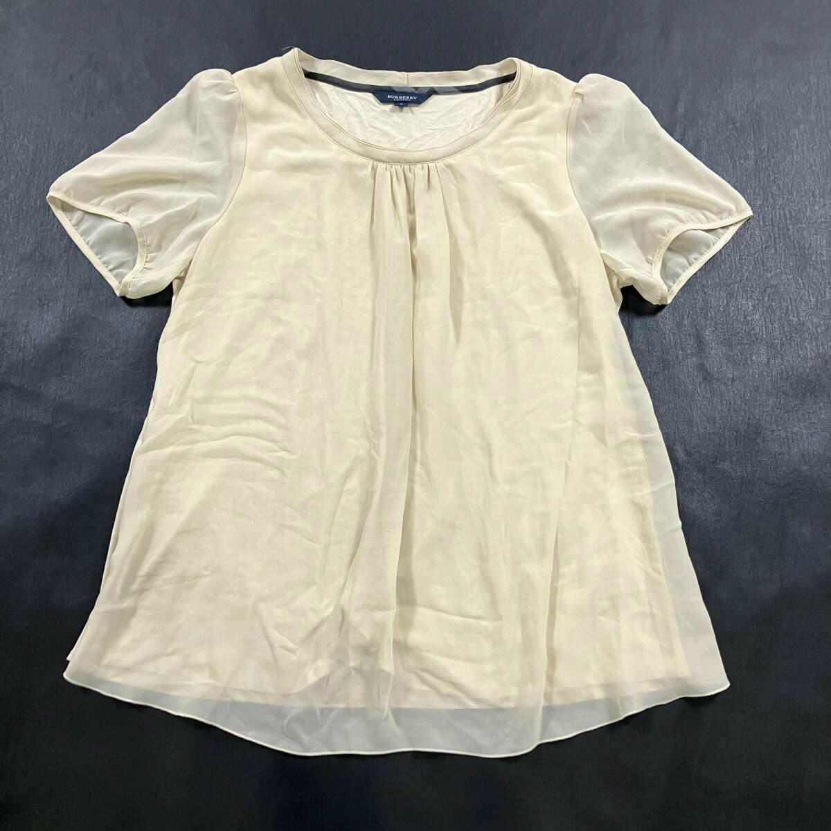 Beige Burberry women's blouse laid flat on a dark background.
