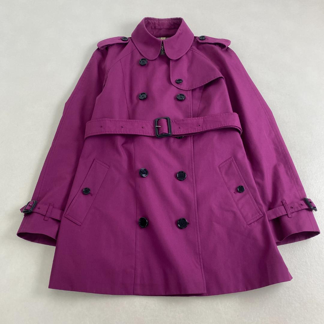 Front view of a women's BURBERRY polyester trench coat in purple with double-breasted buttons, belt, and visible Nova Check lining.
