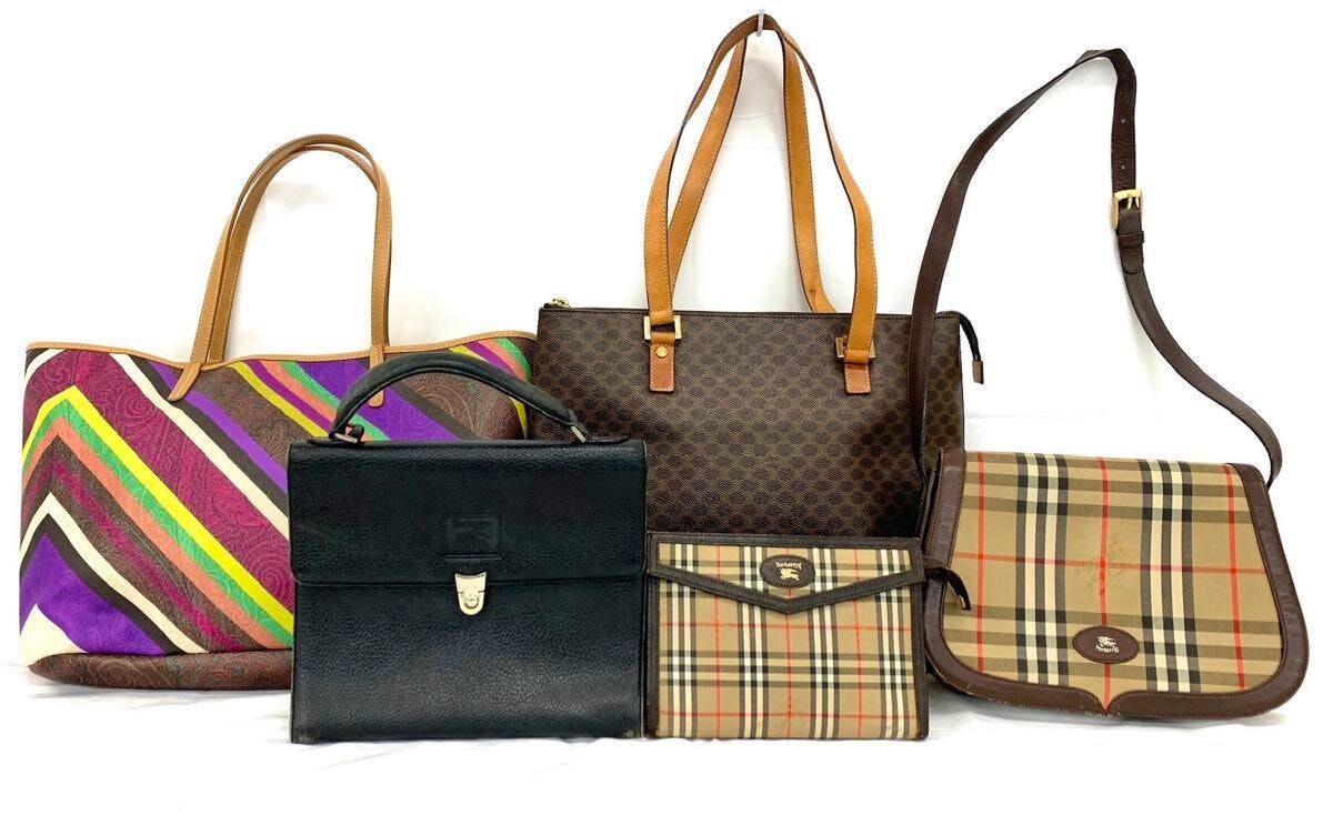Five handbags displayed on a white background: a multicolor striped tote, a black top-handle bag, a brown patterned tote, a small Burberrys check clutch, and a Burberrys check shoulder bag.