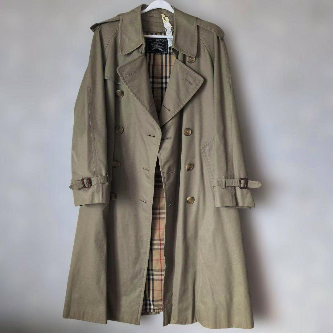 Khaki women's double-breasted trench coat with visible Nova check liner hanging on a hanger.