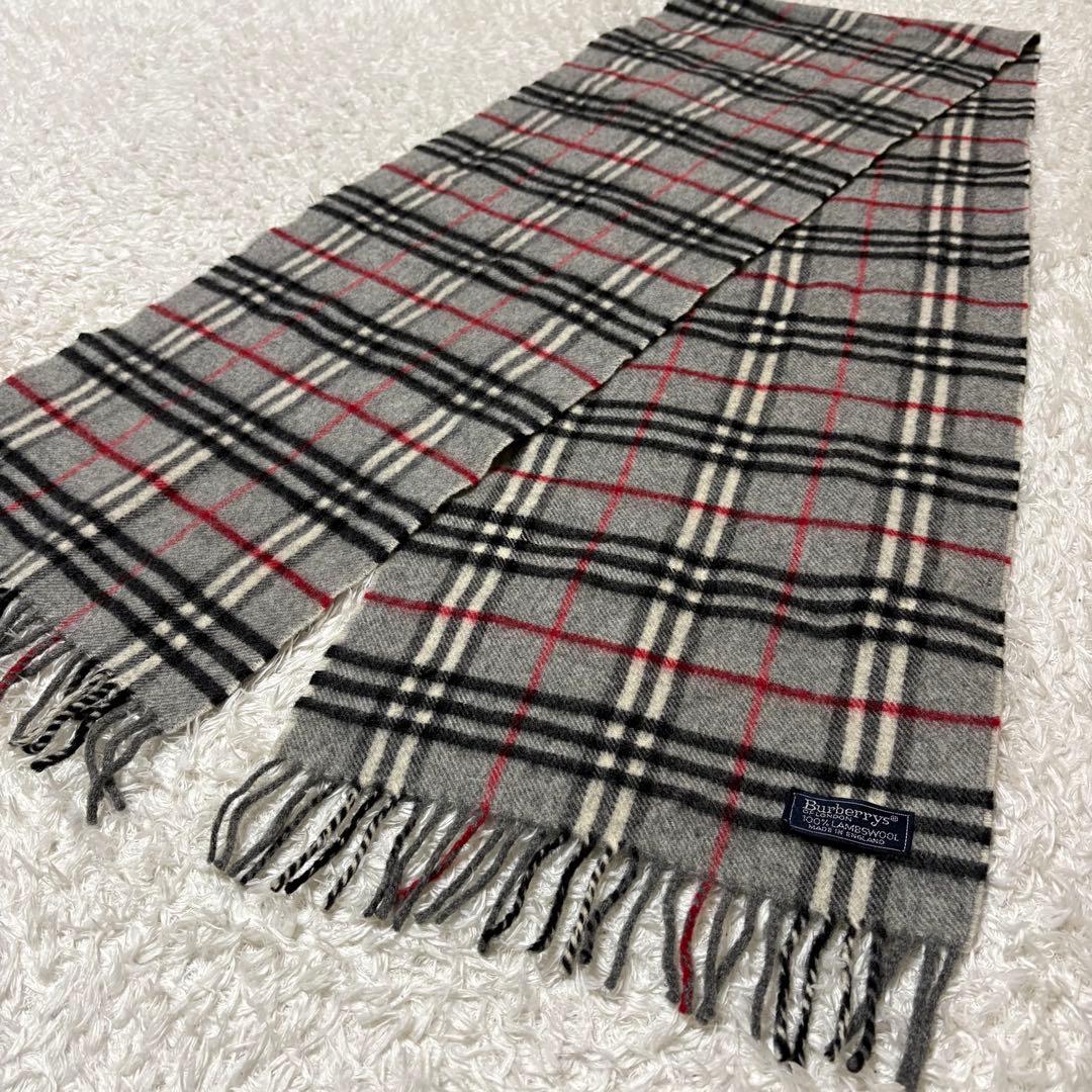 Gray Burberrys wool scarf with Nova check pattern, laid flat showing fringed ends and the brand label.
