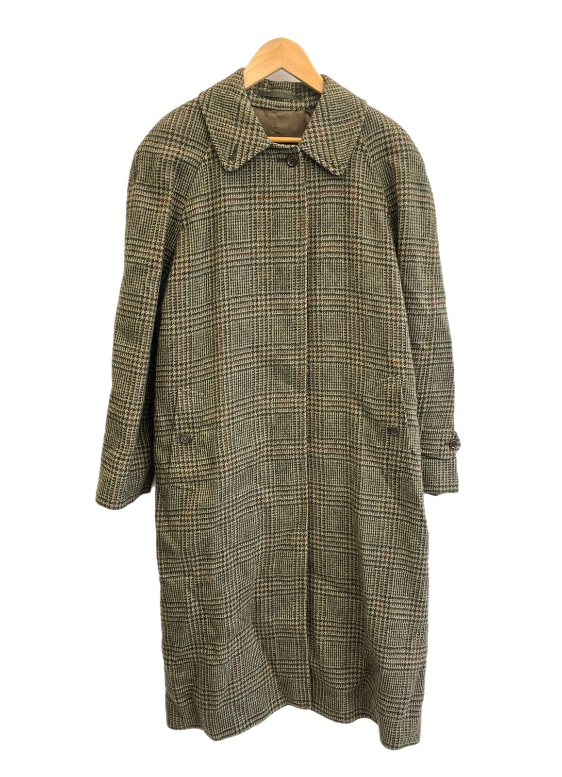 Green glen-check long Burberry coat hanging on a wooden hanger against a white background.