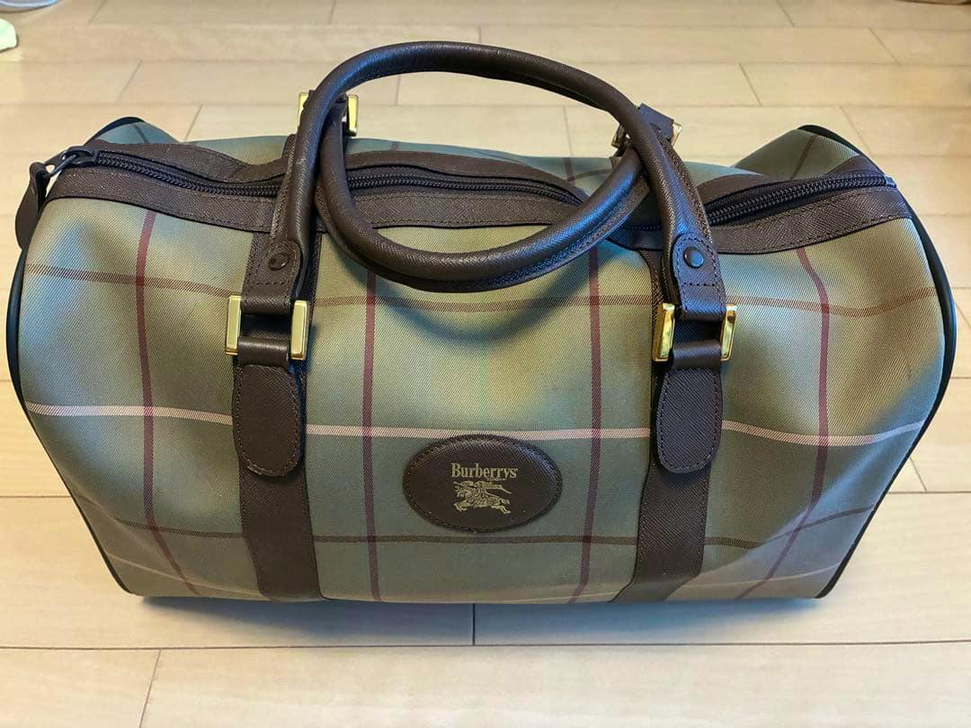 Front view of a green Nova Check Burberrys Boston travel bag with brown leather handles and a Burberrys logo patch.
